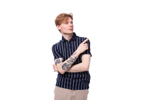handsome 25 year old blond male with tattoos in a striped polo points his finger to the side.