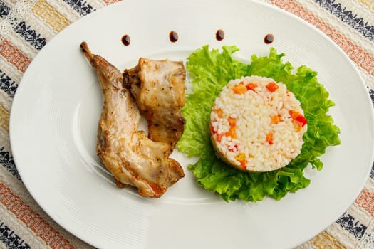 Roasted or fried quail with herbs and rise on a white plate.