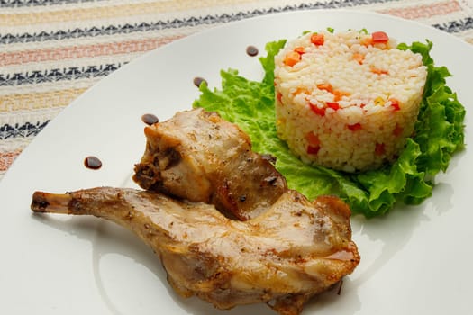 Roasted or fried quail with herbs and rise on a white plate.