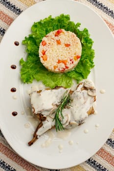 Roasted or fried quail with herbs and rise on a white plate.