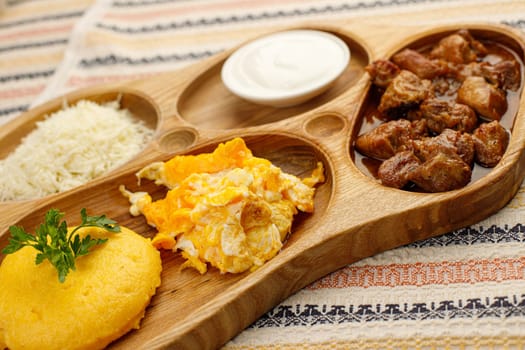 Tochitura is a traditional Romanian dish made from beef and pork with polenta, served on a wood decorative plate.