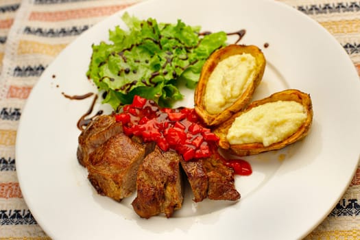 Potato skins loaded with melted cheese, fried pork pieces and roasted bell salad