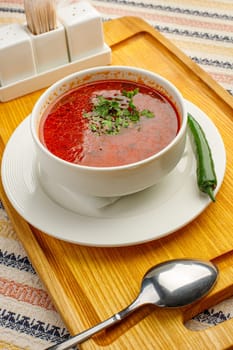 Beetroot soup borsch with garlic, chilly pepper and dill in a white bowl