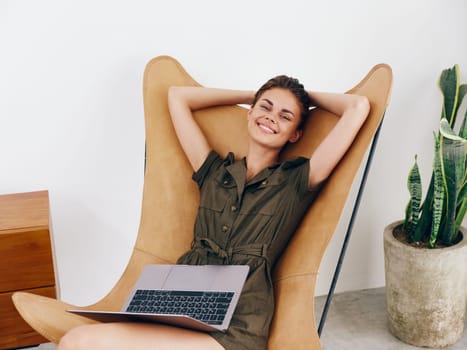 Woman sitting on a chair with a laptop at home beautiful smile and relaxation, modern stylish interior Scandinavian lifestyle, copy space. High quality photo