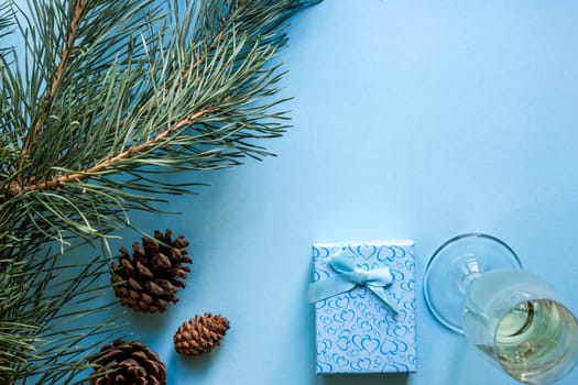 New Year's still life - a glass of champagne, Christmas decorations and spruce branches on blue background. Top view. Copy space. Flat lay