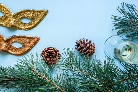 New Year's still life - a glass of champagne, Christmas decorations and spruce branches on blue background. Top view. Copy space. Flat lay