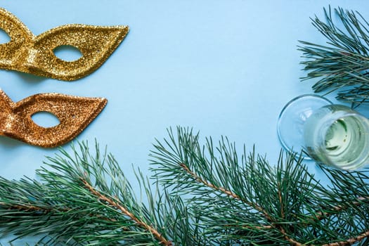 New Year's still life - a glass of champagne, Christmas decorations and spruce branches on blue background. Top view. Copy space. Flat lay