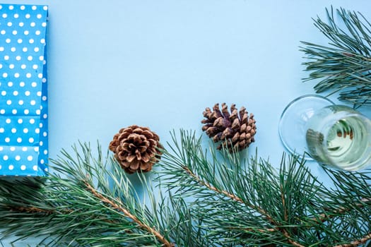 New Year's still life - a glass of champagne, Christmas decorations and spruce branches on blue background. Top view. Copy space. Flat lay