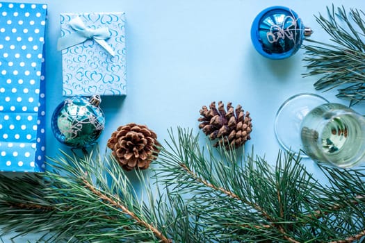 New Year's still life - a glass of champagne, Christmas decorations and spruce branches on blue background. Top view. Copy space. Flat lay