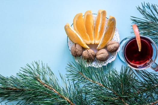 Hot mulled wine with orange, anise, cardamon and cinnamon on blue background. Christmas tree branches, gifts and cones. Flat lay, copy space, top view. Holidays.