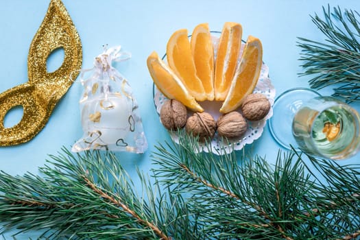 New Year's still life - a glass of champagne, Christmas decorations and spruce branches on blue background. Top view. Copy space. Flat lay