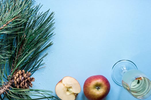 New Year's still life - a glass of champagne, Christmas decorations and spruce branches on blue background. Top view. Copy space. Flat lay