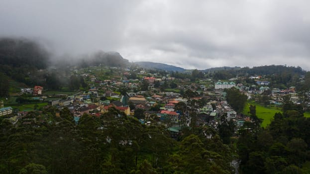 Aerial view of city of Nuwara Eliya is covered with clouds among green hills and mountains. Sri Lanka.