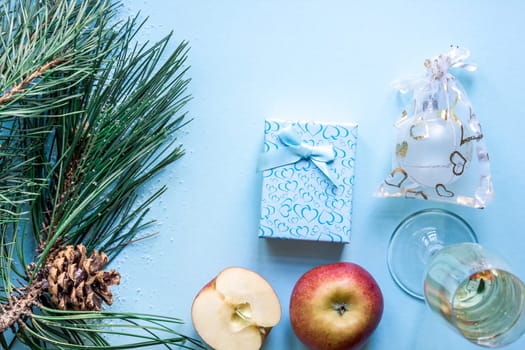 New Year's still life - a glass of champagne, Christmas decorations and spruce branches on blue background. Top view. Copy space. Flat lay