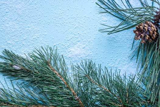Christmas decoration. Branch christmas tree and cones spruce on snow on blue background. Top view, flat lay