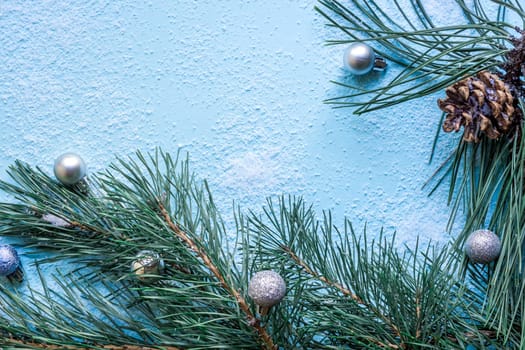Christmas decoration. Branch christmas tree and cones spruce on snow on blue background. Top view, flat lay