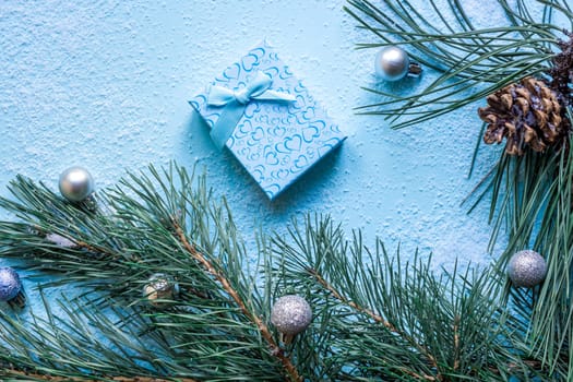 Christmas decoration. Branch christmas tree and cones spruce on snow on blue background. Top view, flat lay