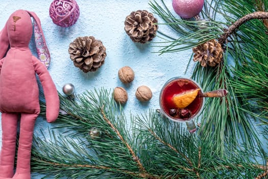 Hot mulled wine with orange, anise, cardamon and cinnamon on blue background. Christmas tree branches, gifts and cones. Flat lay, copy space, top view. Holidays.