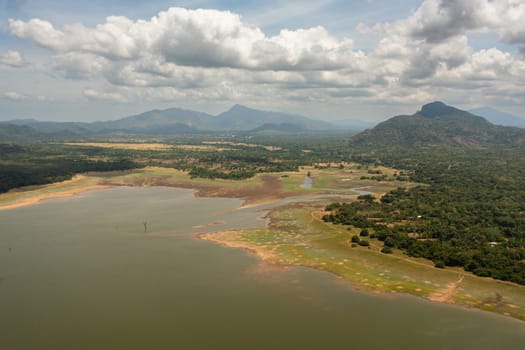 Aerial view of lake in a valley among tropical vegetation. Kandalama Reservoir in Sri Lanka.