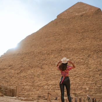 Tall Beautiful Young Girl Looking at the Pyramid of Giza in sunshine. High quality photo
