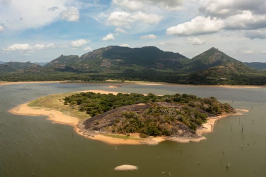 Aerial view of island and a lake in the jungle in a mountain valley. Kandalama Reservoir in Sri Lanka.