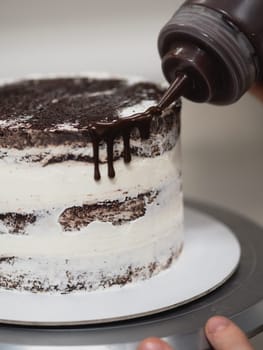 pastry chef preparing a chocolate frosted dripped icing cup cake with sweet fruit topping and golden brush strokes