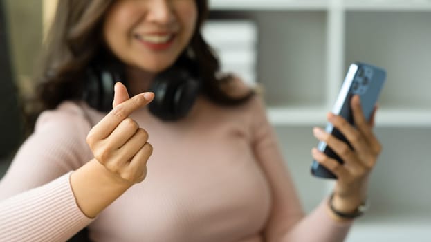 Select focused on hand of smiling woman making mini heart sign of love, romance and happiness concept.