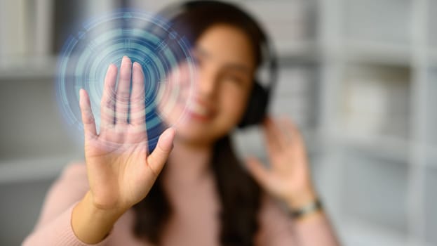 Smiling young woman wearing headphone, pressing button on virtual screen. Future technology, innovation and cyberspace.