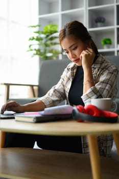 Focused young woman calculating domestic expenses, utility bills at home. Finance management concept.