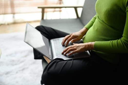 Young woman hands using laptop, typing on keyboard, chatting, shopping online from home.