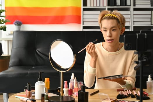 Portrait of transgender male beauty blogger recording makeup tutorial in home studio. LGBTQ, blogging, makeup and lifestyle concept.