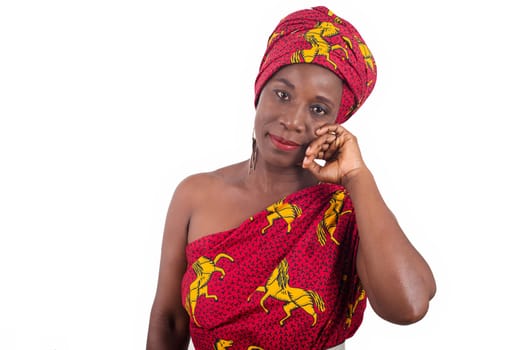 young african woman standing in loincloth in a studio hand on cheek staring at camera smiling.