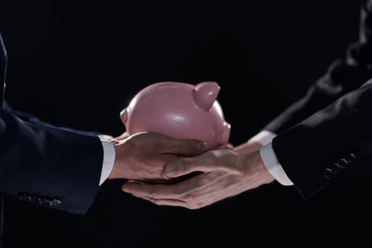 A businessman gives you a piggy bank isolated on a black background. banking