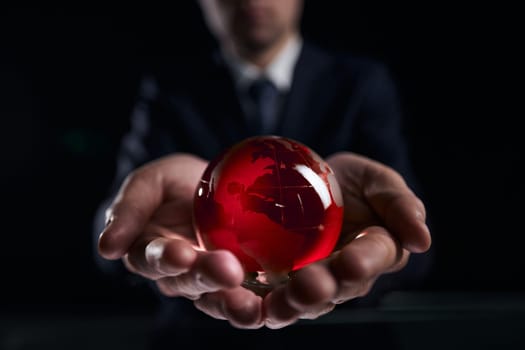 businessman holds glass globe with continents in hands
