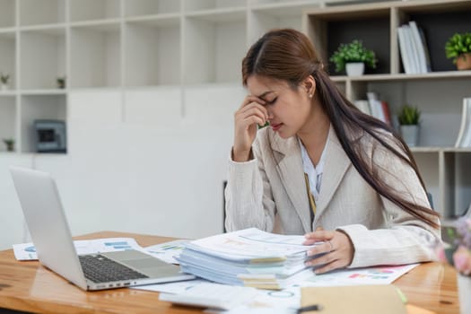 Business women are stressed while working on laptop and pile of documents, Tired businesswoman with headache at office, feeling sick at work.