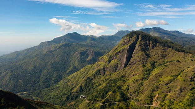 Aerial view of Mountains covered with forest against a background of blue sky and clouds. Mountainous terrain in Sri Lanka.