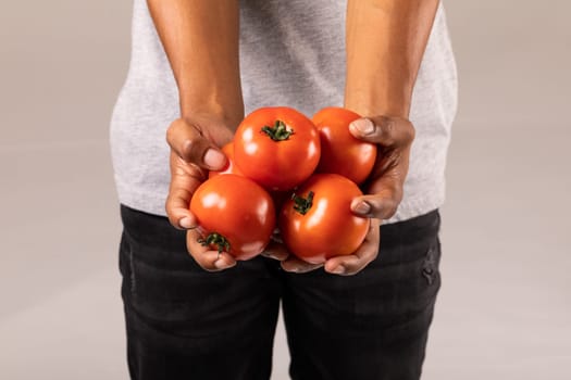 Midsection of man holding fresh red tomatoes standing against white background. unaltered, lifestyle, organic food and healthy eating concept.