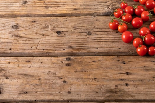 Overhead view of fresh red cherry tomatoes on brown wooden table. unaltered, organic food and healthy eating concept.