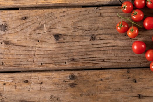 Overhead view of fresh cherry tomatoes on brown wooden table. unaltered, organic food and healthy eating concept.