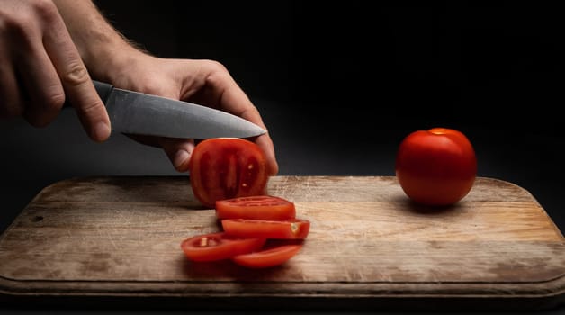 Cherry tomatoes on wooden board cut with knife by female hands on background with copyspace. Healthy organic pomodoro vegetable sliced