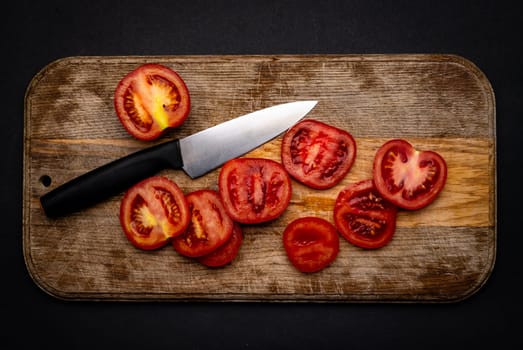 Sliced cherry tomatoes with knife on wooden board on background with copyspace. Healthy organic pomodoro vegetable for bruschetta view from above