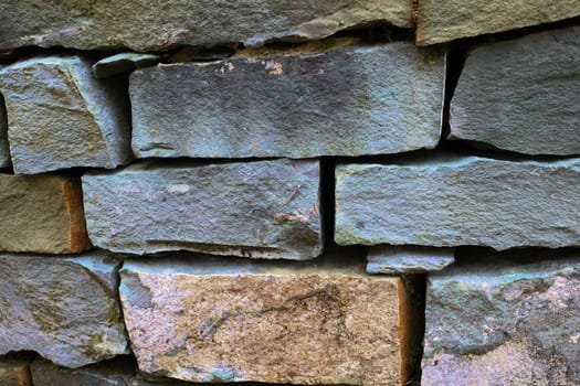 An old dry stone slate garden wall. The stones are stacked. The color is mainly grey