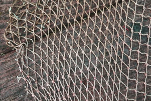 Part of a knotted fishing net on a dark wooden background