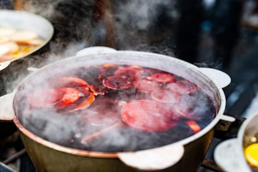 Beverages berries hot mulled wine in pots in street food market at Christmas time. Colorful festive hot drinks at fair xmas festival outdoors closeup