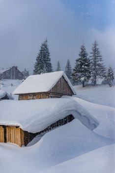 Fantastic winter landscape with wooden house in snowy mountains.