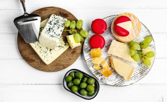 Different kinds of cheese served with green olives, tomato and grape for gourmet nutrition. Organic parmesan and brie delicatessen