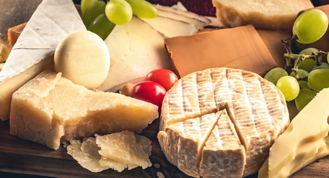 Parmesan and different kinds of cheese served with grapeand honey closeup. Organic brie and camambert set delicatessen collection