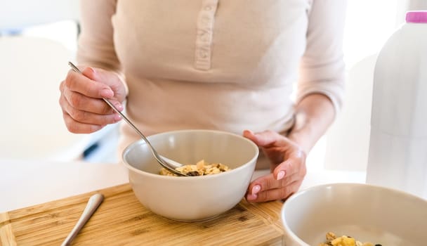 Girl eating muesli at breakfast at the kitchen
