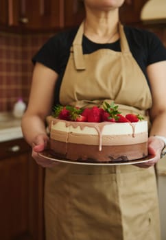 Details: Triple chocolate sweet dessert of white, milk and dark chocolate mousse layers, decorated with ruby pink glaze and fresh ripe strawberries. Birthday cake. Confectionery. Culinary. Food art