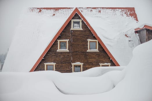 The roof of a wooden house. Large snow drifts. Triangular roof with windows